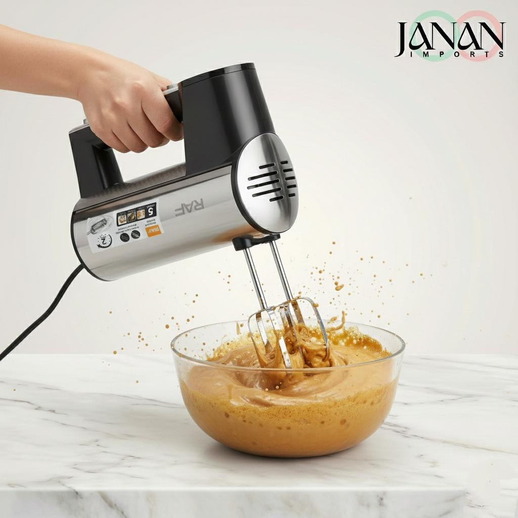 Hand mixer being used to blend a creamy mixture in a glass bowl on a marble surface with 'Janan Imports' branding.